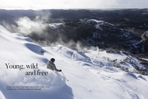 Skier carving through fresh powder on a snow-covered slope at Perisher Ski Resort, overlooking the Snowy Mountains, featured in the Vacations & Travel magazine article "Young, Wild and Free".