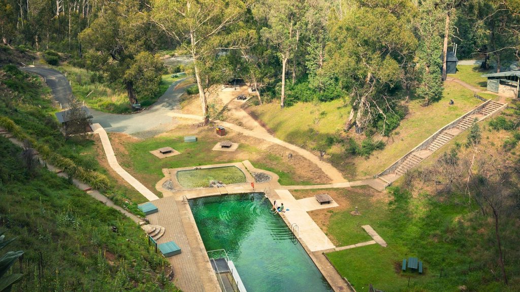Aerial view of the Yarrangobilly Caves thermal pool surrounded by bushland in Kosciuszko National Park, NSW.